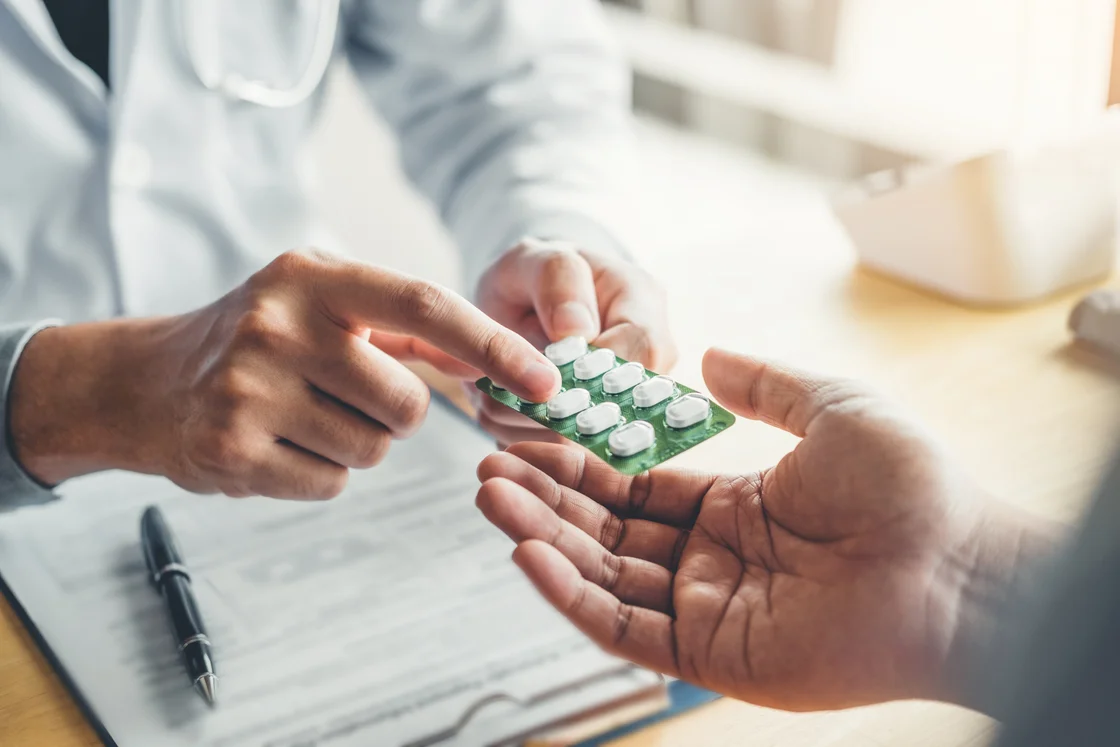 A healthcare professional explaining a blister pack of medicine to a patient A healthcare professional explaining a blister pack of medicine to a patient
