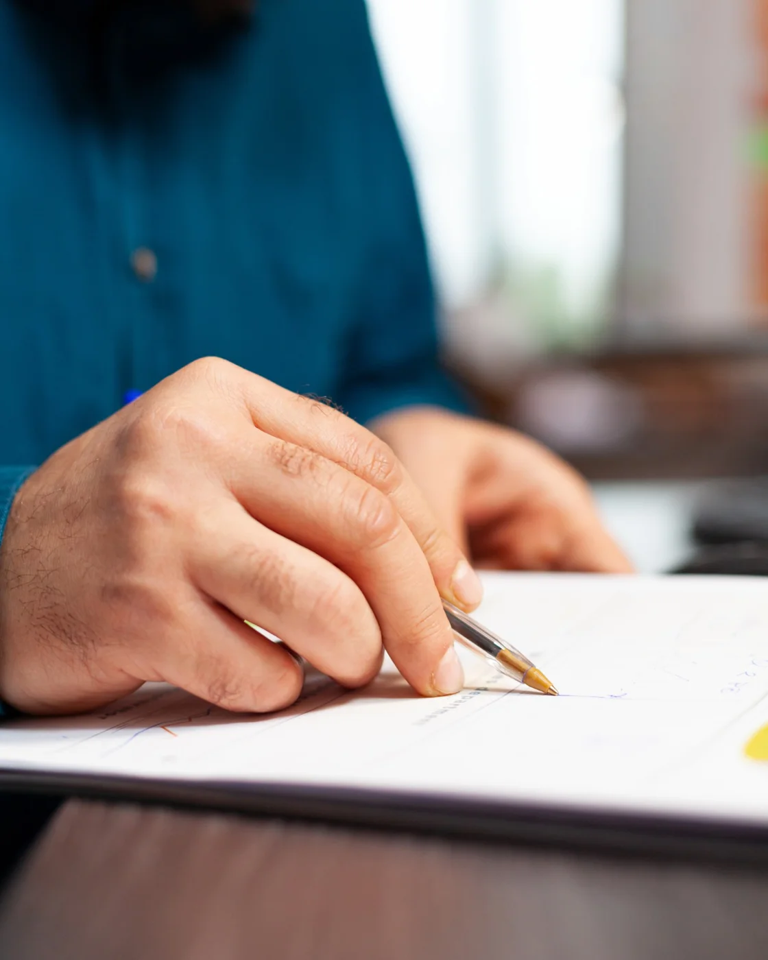 A hand writing on a document with a pen